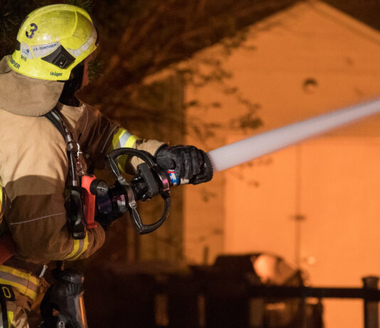 Oceanside Housefire Harms 1, Displaces 13 firefighter works to extinguish flames of house fire